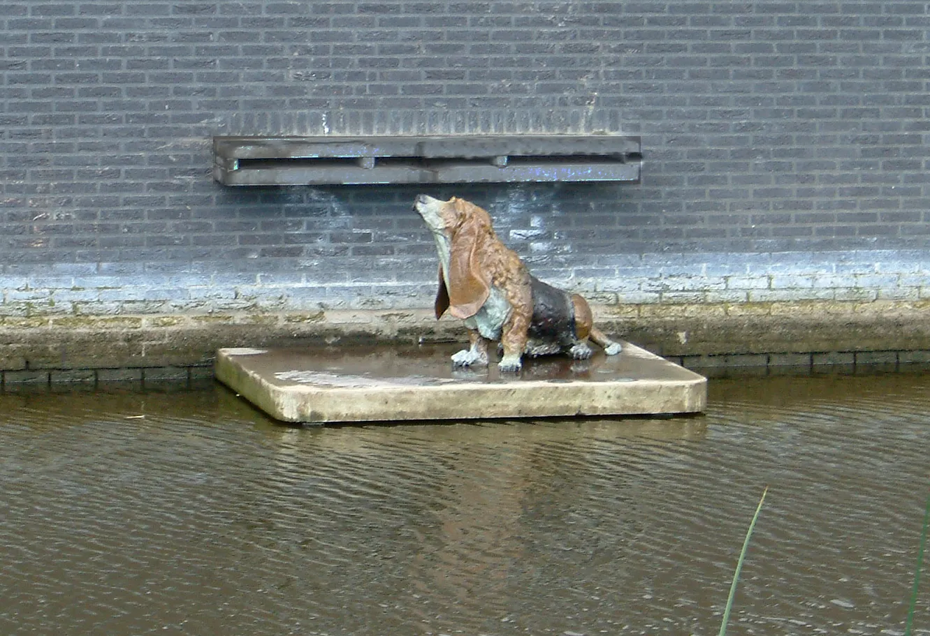 Bronzen Basset Hound onder water spuwer (vanaf de overkant)